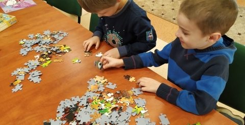 Na zdjęciu uczestnicy zajęć w Bibliotece układają puzzle.