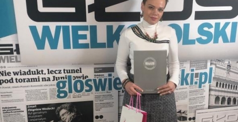 Na zdjęciu Monika Binkiewicz z dyplomem i nagrodą na tle ścianki prasowej Głosu Wielkopolskiego.