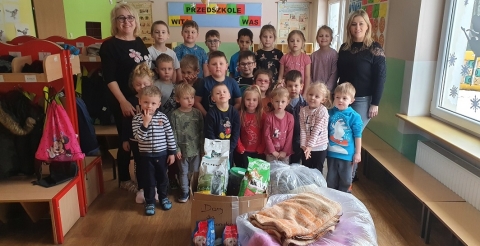 Na zdjęciu grupa dzieci z przedszkola w Podrzewiu z nauczycielkami i zgromadzonymi darami dla schroniska