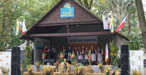 Zespół Duszniczanka gra i śpiewa na scenie w parku w Dusznikach podczas Dożynek Gminnych 2021.