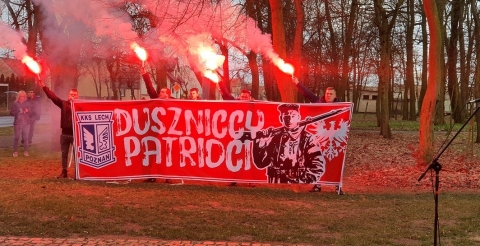 Na zdjęciu duszniccy kibice Lecha Poznań z banerem i zapalonymi racami.