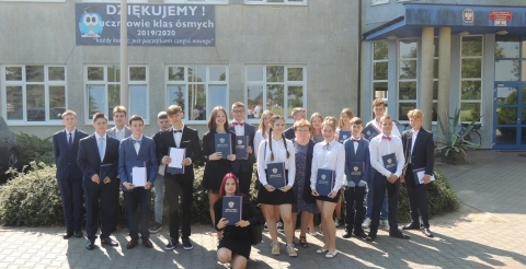 Na zdjęciu uczniowie klas ósmych ze Szkoły Podstawowej w Dusznikach, w tle baner z podziękowaniami.