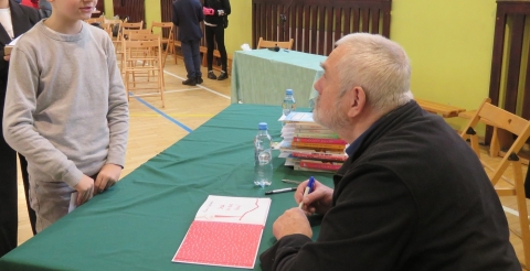 Pisarz podpisuje książkę uczniowi SP Grzebienisko